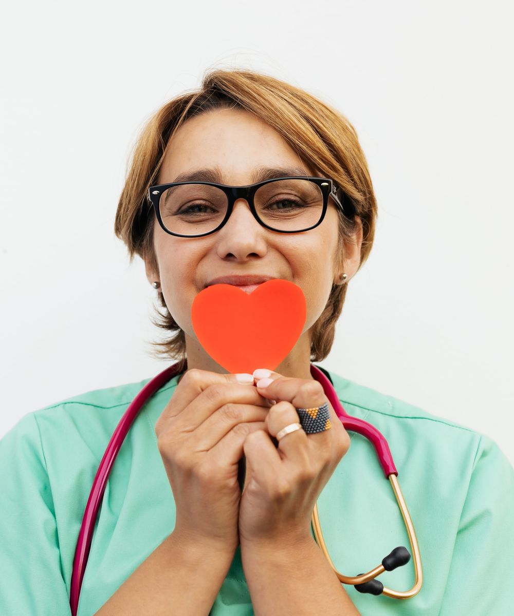 Cardiologist in a white coat holding a red heart model